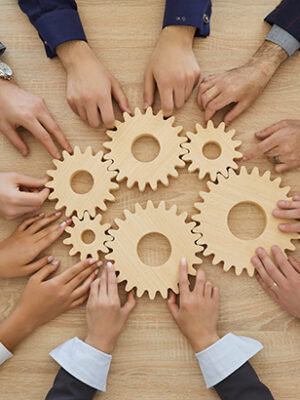 Team of people join cogwheels as metaphor for teamwork and effective business system